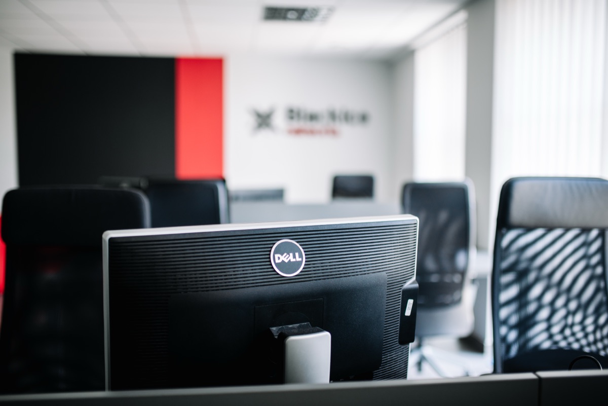 Stanowiska z monitorami w biurze BlackIce Networks, w tle logo firmy na ścianie